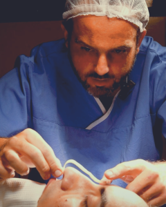 Médico concentrado durante cirurgia de rinoplastia, encaixo molde impresso em 3D no nariz da paciente.