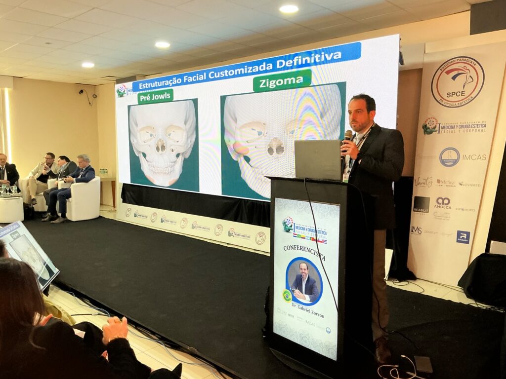 Imagem do Dr Gabriel Zorron, cirurgião especialista em face, palestrando sobre os implantes faciais customizados no congresso de medicina. ele fala para outros médicos de todo o mundo em sua aula.